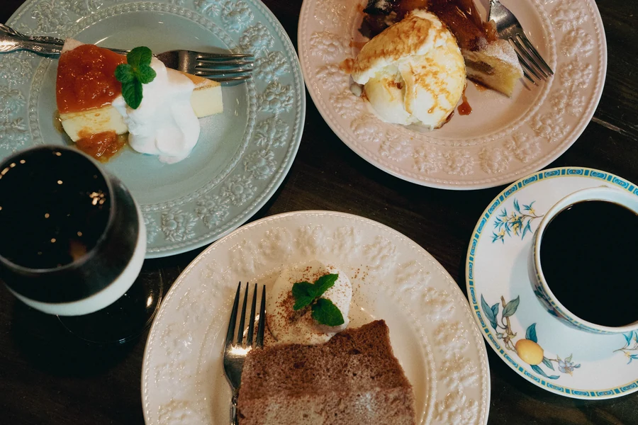 喫茶店のテーブルを真上から。チーズケーキ、アイスクリーム、シフォンケーキと珈琲